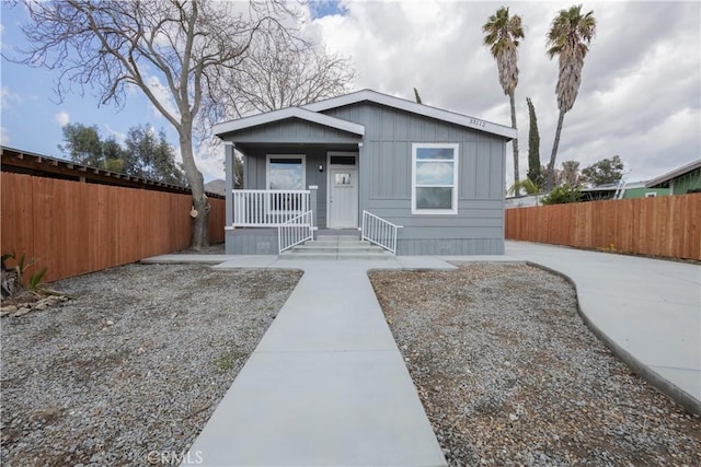 view of front of property with board and batten siding, covered porch, and fence