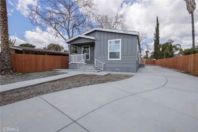 view of front of house featuring driveway, fence, a porch, and board and batten siding