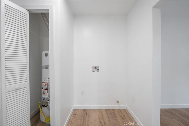 clothes washing area featuring laundry area, light wood-style flooring, and baseboards