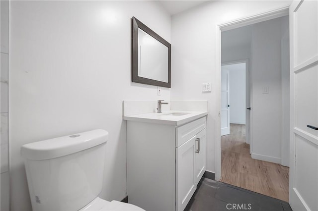 bathroom with toilet, baseboards, and vanity