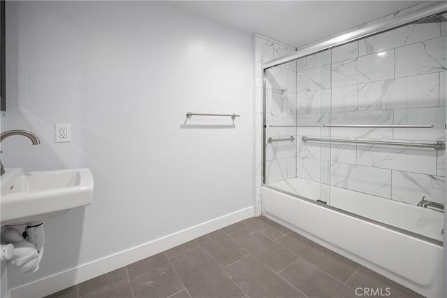 bathroom with bath / shower combo with glass door and baseboards