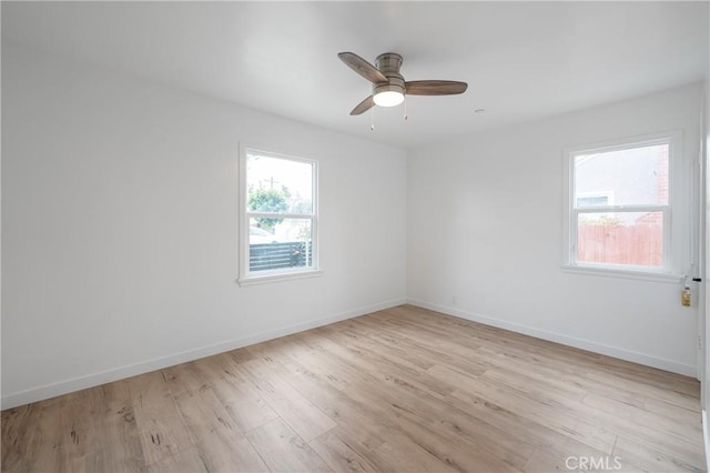 spare room with light wood-type flooring, plenty of natural light, and baseboards