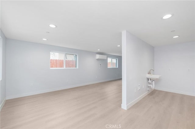 basement with light wood finished floors, recessed lighting, baseboards, and a wall mounted AC