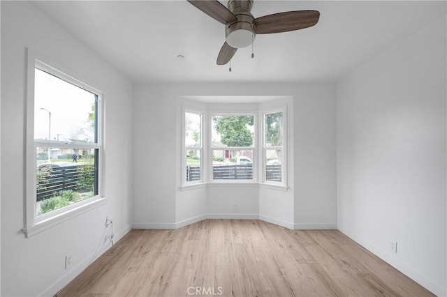 unfurnished room featuring light wood-style floors, ceiling fan, and baseboards