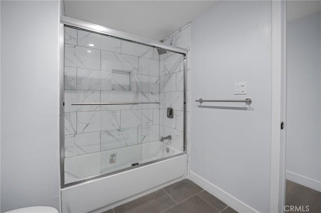 full bath with tile patterned flooring, combined bath / shower with glass door, toilet, and baseboards