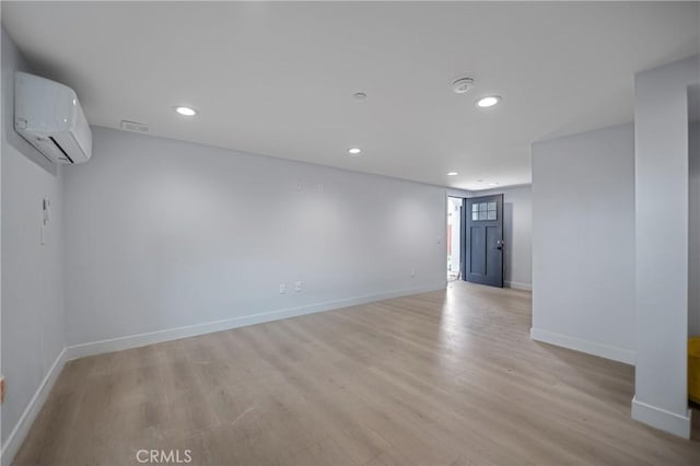 spare room featuring baseboards, an AC wall unit, light wood-style flooring, and recessed lighting