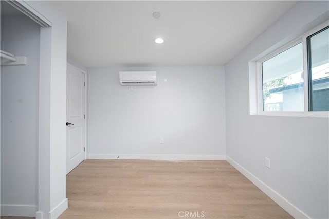 interior space with a wall unit AC, light wood-style floors, baseboards, and recessed lighting