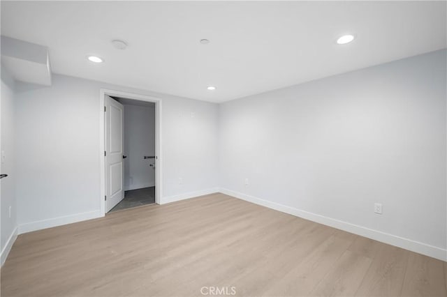 spare room featuring light wood finished floors, recessed lighting, and baseboards