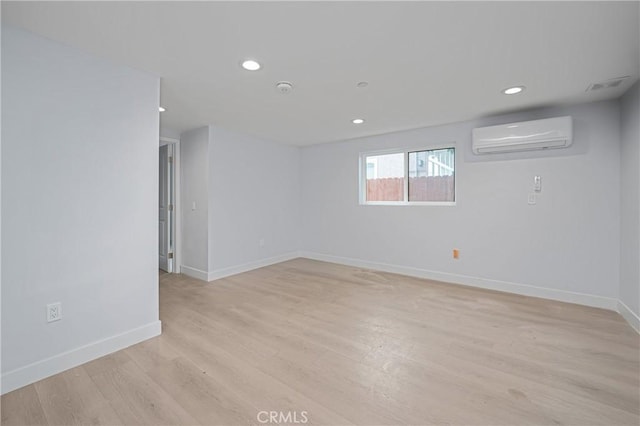 below grade area with a wall unit AC, light wood-style flooring, baseboards, and recessed lighting