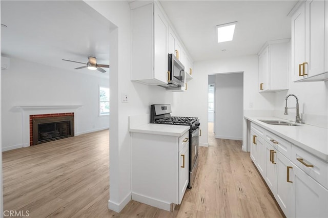 kitchen with stainless steel appliances, a sink, light countertops, and white cabinetry