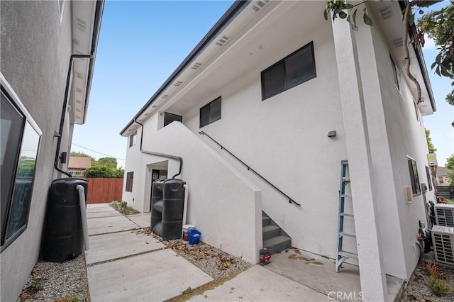 view of property exterior with a patio area, fence, and stucco siding