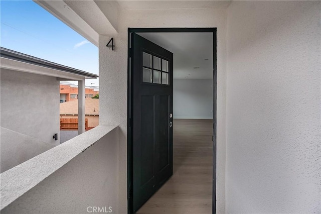 view of exterior entry featuring a balcony and stucco siding