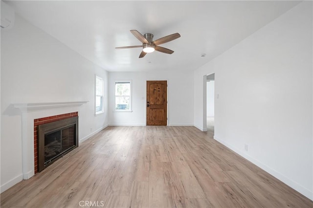 unfurnished living room with light wood-style flooring, a fireplace, baseboards, and a ceiling fan