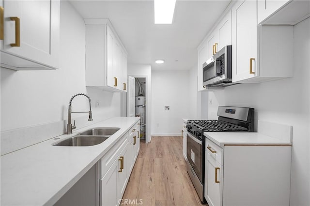 kitchen featuring white cabinetry, stainless steel appliances, a sink, and light countertops