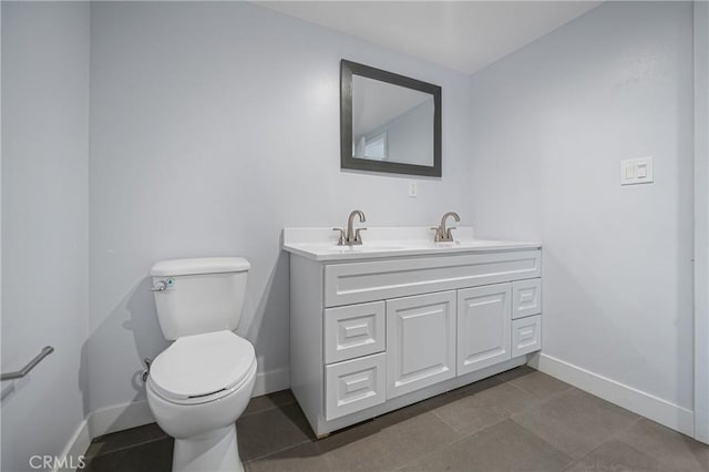 bathroom featuring baseboards, a sink, toilet, and double vanity