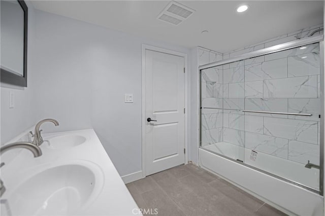 bathroom with visible vents, a sink, combined bath / shower with glass door, and double vanity