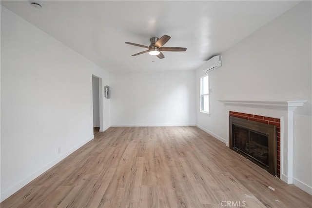 unfurnished living room with a wall unit AC, a brick fireplace, ceiling fan, light wood-type flooring, and baseboards