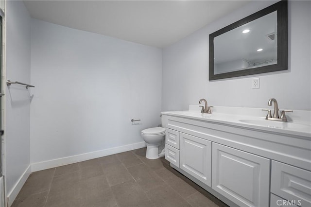 bathroom with toilet, double vanity, baseboards, and a sink