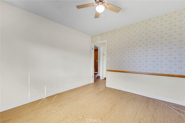 empty room featuring light wood-style floors, ceiling fan, baseboards, and wallpapered walls