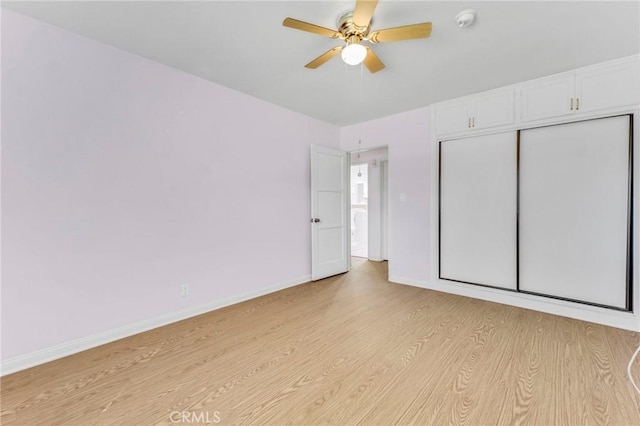 unfurnished bedroom featuring baseboards, a closet, a ceiling fan, and light wood-style floors