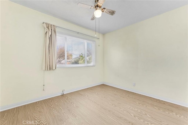 spare room with ceiling fan, light wood-type flooring, and baseboards