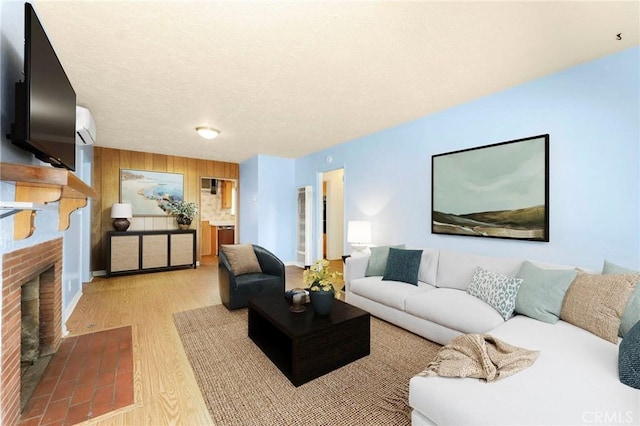 living area with wooden walls, wood finished floors, a textured ceiling, an AC wall unit, and a fireplace