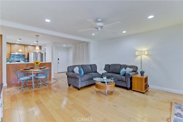 living room featuring light wood-style floors, recessed lighting, baseboards, and a ceiling fan