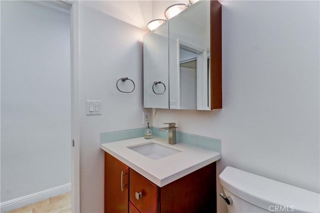 bathroom featuring toilet, wood finished floors, vanity, and baseboards