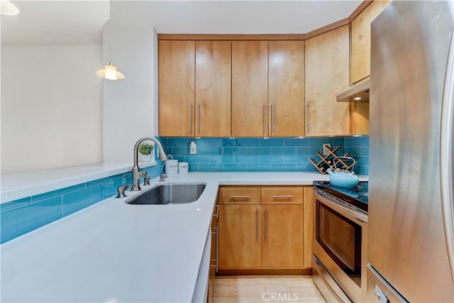 kitchen with under cabinet range hood, tasteful backsplash, appliances with stainless steel finishes, and a sink