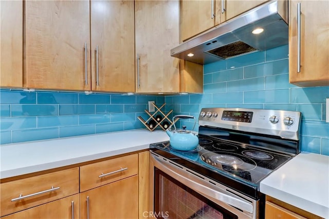 kitchen with light countertops, stainless steel range with electric cooktop, under cabinet range hood, and decorative backsplash