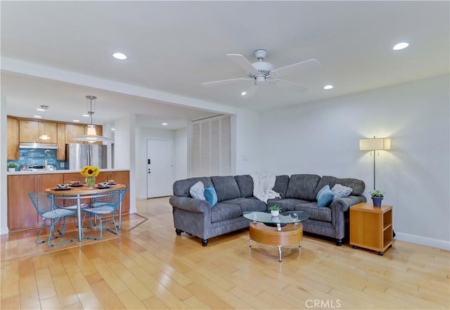 living area featuring recessed lighting, baseboards, light wood finished floors, and ceiling fan