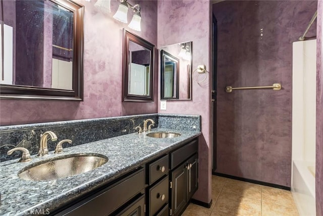 bathroom with double vanity, a sink, baseboards, and tile patterned floors