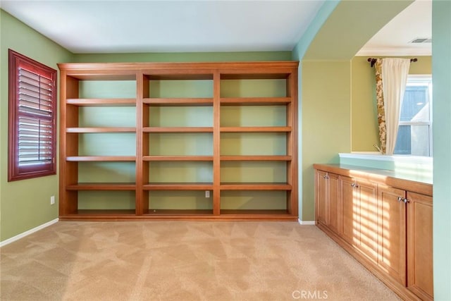 interior space featuring baseboards, visible vents, and light colored carpet