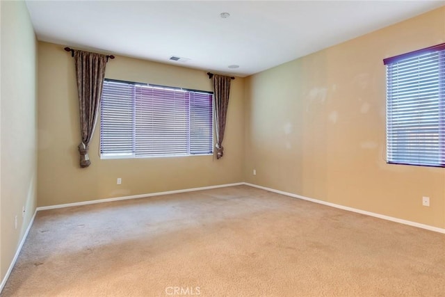 carpeted empty room featuring visible vents and baseboards