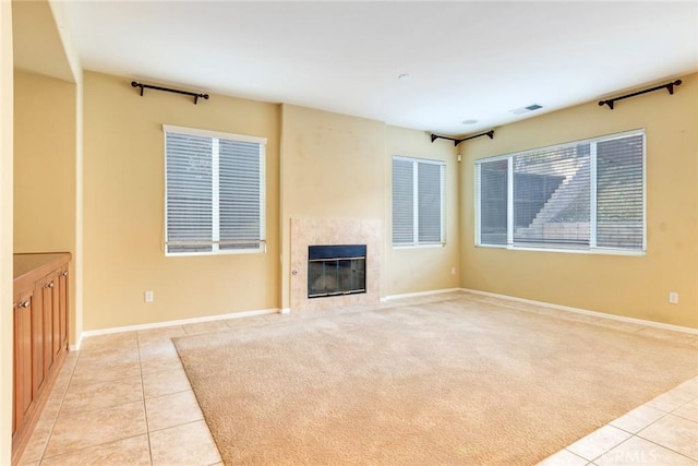 unfurnished living room featuring light tile patterned floors, light carpet, a premium fireplace, visible vents, and baseboards