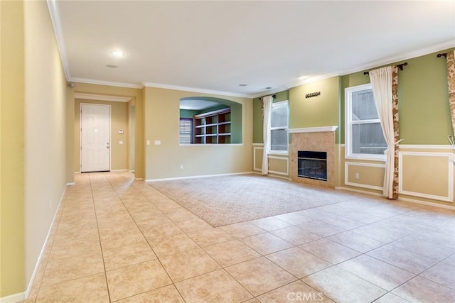 unfurnished living room featuring tile patterned flooring, baseboards, crown molding, and a tiled fireplace