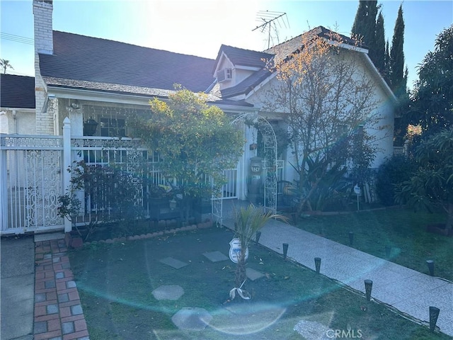 view of front of home featuring a shingled roof, fence, and a chimney