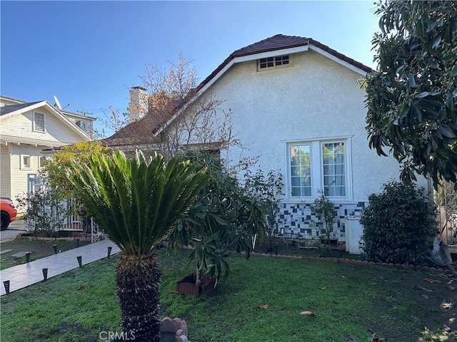 view of side of home featuring a lawn and stucco siding