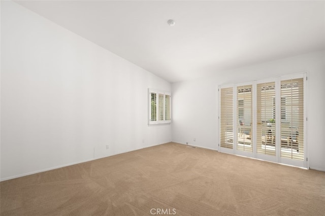 unfurnished room with vaulted ceiling and light colored carpet