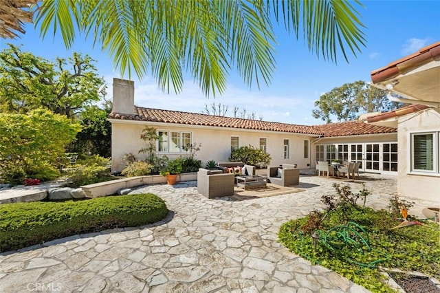 exterior space with an outdoor living space, a chimney, a patio, and stucco siding