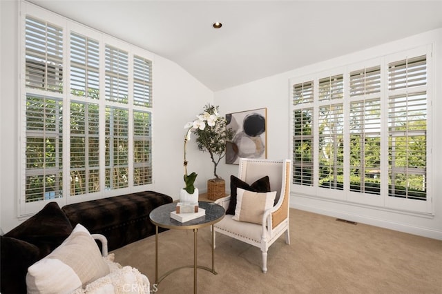 living area featuring a wealth of natural light, visible vents, carpet floors, and vaulted ceiling