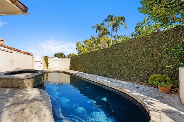 view of pool with a fenced backyard and a pool with connected hot tub