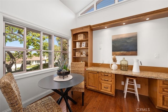 office space with dark wood finished floors, built in desk, and high vaulted ceiling