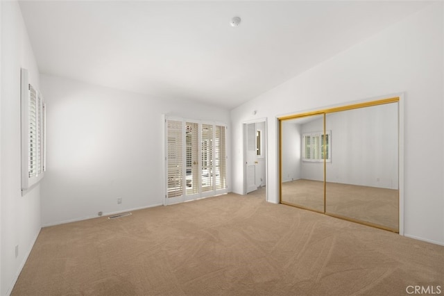 unfurnished bedroom with lofted ceiling, carpet, and visible vents