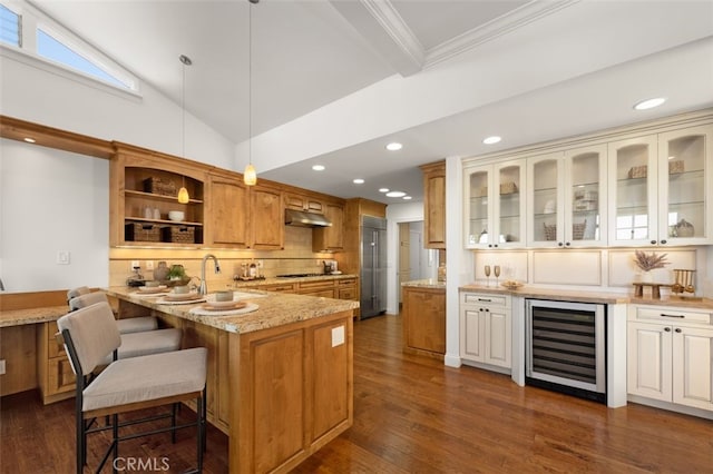 kitchen featuring glass insert cabinets, light stone countertops, beverage cooler, under cabinet range hood, and a peninsula