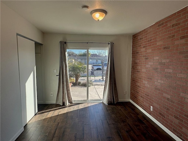 entryway featuring brick wall, baseboards, and dark wood finished floors