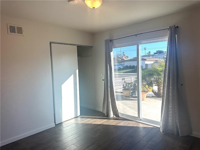 empty room featuring baseboards, visible vents, and wood finished floors