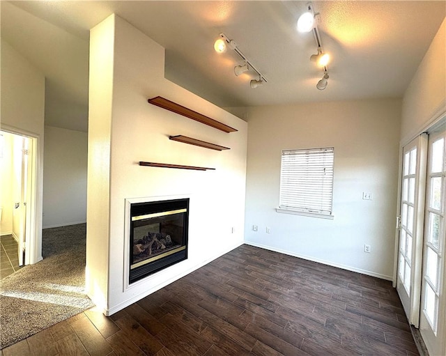 unfurnished living room with a glass covered fireplace, dark wood finished floors, and baseboards