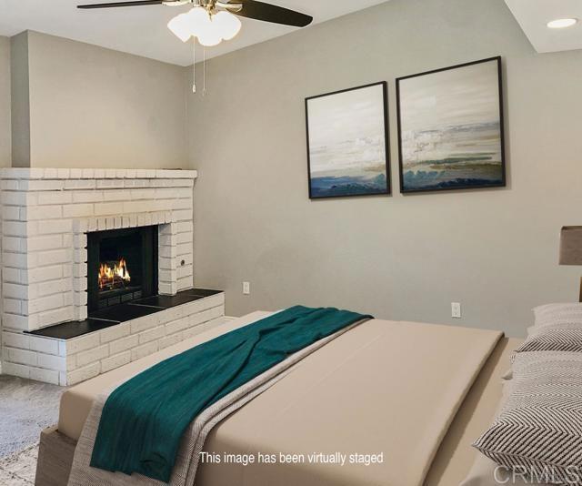 bedroom with a brick fireplace and a ceiling fan