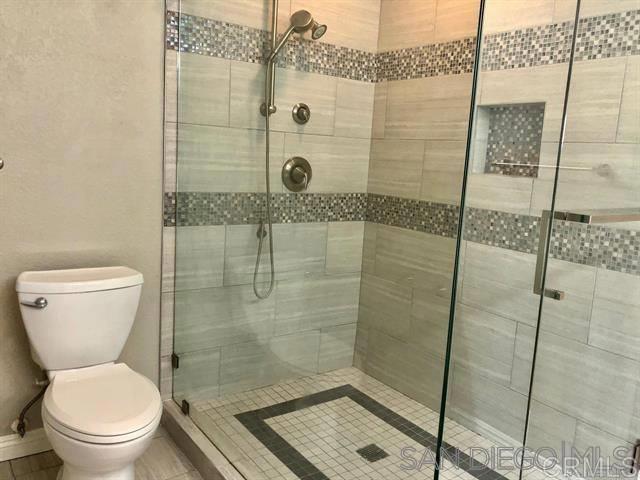 full bath with baseboards, toilet, and a shower stall